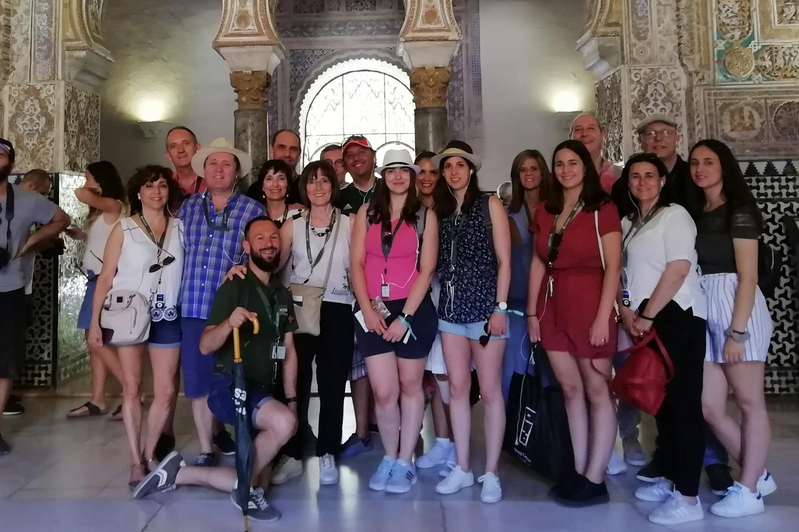 Grupp leende turister som poserar framför Alcázar de Sevilla